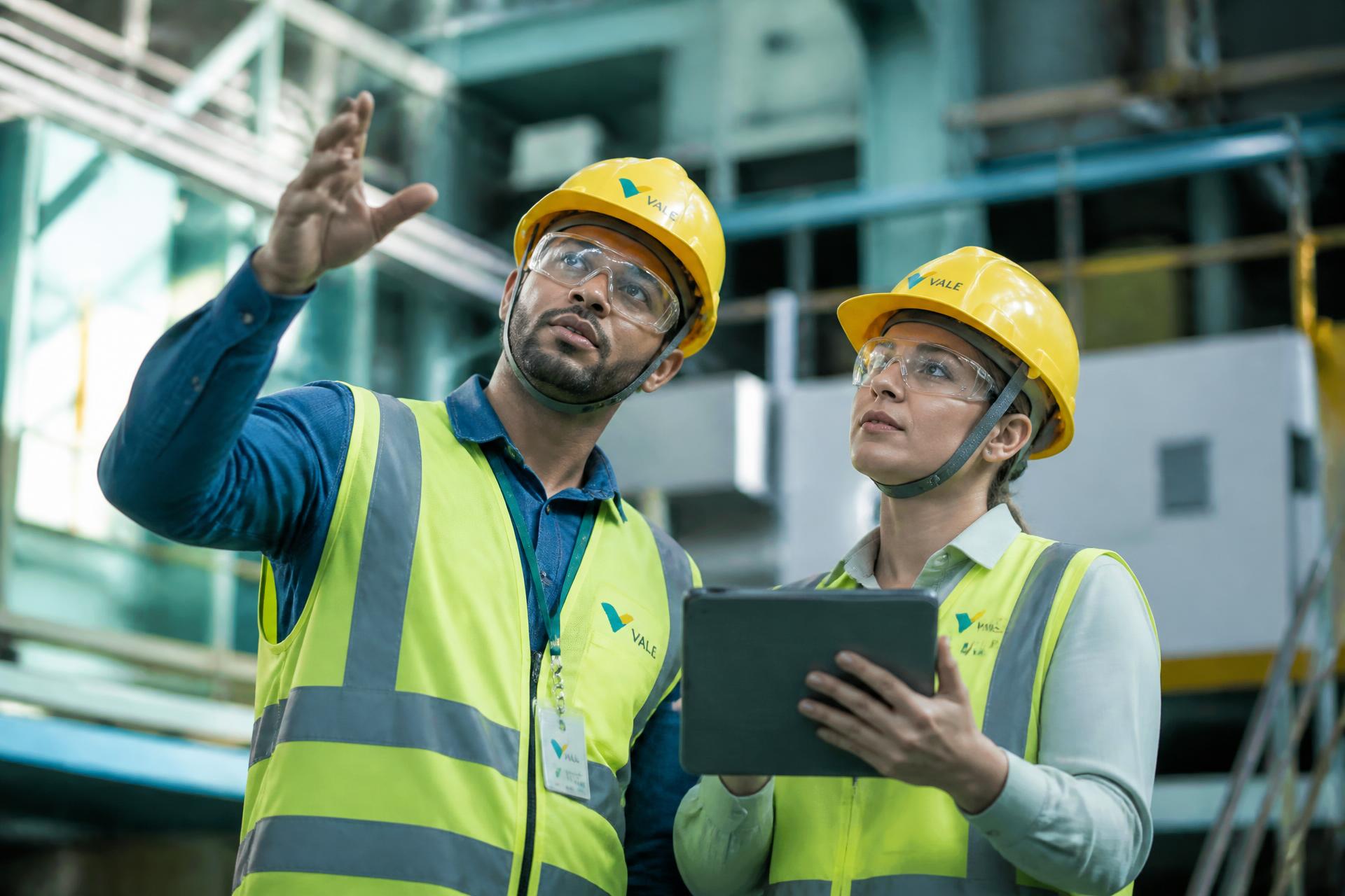 Profissionais de segurança do trabalho com EPIs em ambiente industrial